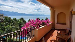 un balcón con flores rosas y vistas al océano. en Velas Vallarta, en Puerto Vallarta