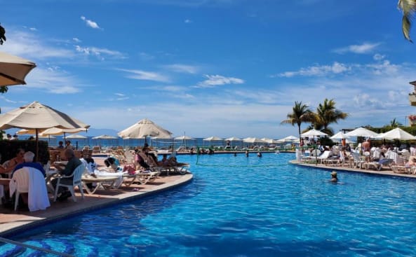 una piscina en un complejo con gente sentada en sillas en Velas Vallarta, en Puerto Vallarta