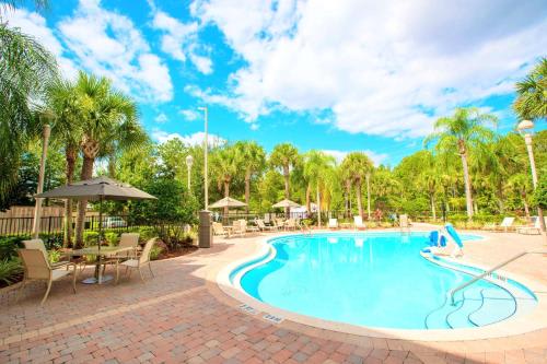 una piscina en un complejo con mesas, sillas y palmeras en Best Western Plus Orlando Lake Buena Vista South Inn & Suites, en Kissimmee