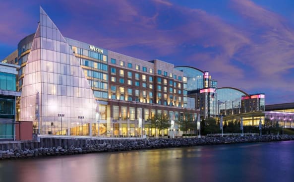 un edificio con una fachada de cristal junto a una masa de agua en The Westin Washington National Harbor, en National Harbor