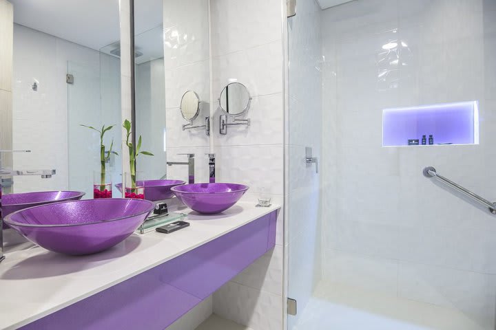 Baño con ducha y doble lavabo en una habitación