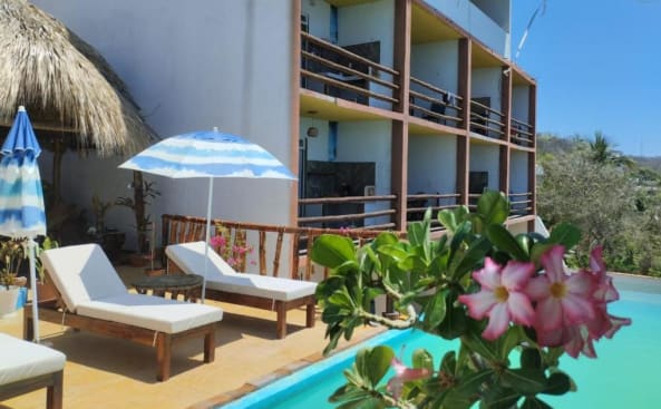 un complejo con piscina, sillas y un edificio en Namasté Zipolite Suites en Zipolite