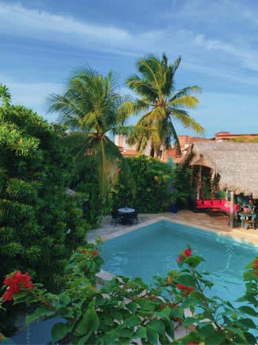 una piscina en un patio con palmeras en el Hotel de Charme Castelinho, en Canoa Quebrada
