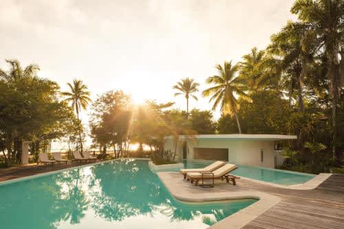 una piscina con sillas y una casa con palmeras en Auka Boipeba, en la Isla de Boipeba