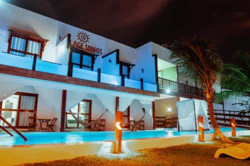 un gran edificio blanco con piscina por la noche en la Pousada Village Sonhos Camocim, en Camocim