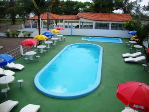 una piscina con sillas, sombrillas y sombrillas en el Hotel Pousada Terras do Sem Fim, en Ilhéus