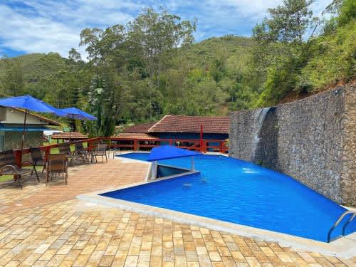 una piscina con sombrillas azules junto a un edificio del Hotel Fazenda Bonanza, en Engenheiro Paulo de Frontin