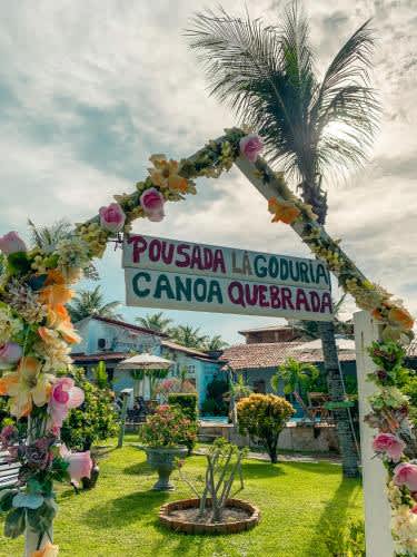 un letrero para un resort con una palmera en la Pousada La Goduria, en Canoa Quebrada