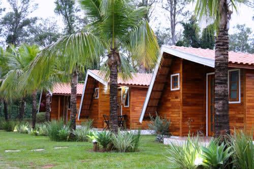 una casa de madera con una palmera frente a ella en la Pousada Monte Carlo, en Olímpia