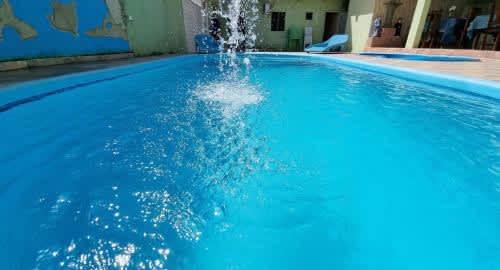 una piscina azul con una fuente de agua en la Pousada Nossa Senhora Das Dores, en Maragogi