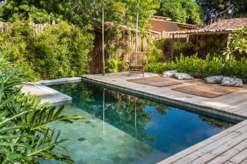 una piscina con terraza y una silla en el patio trasero de la Casa das Conchas Caraiva, en Caraíva