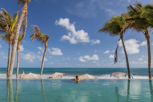 una persona en una piscina en una playa bordeada de palmeras del Saline Taíba Boutique Beach Hotel, en Taíba