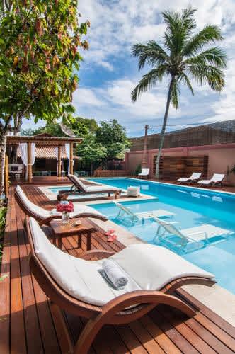 una piscina con tumbonas en una terraza de madera de la Pousada Quarto Crescent, en Trancoso
