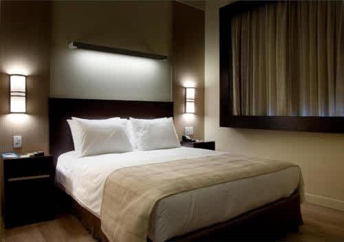 1 dormitorio con 1 cama de matrimonio con almohadas blancas en Master Cosmopolitan Moinhos de Vento, en Porto Alegre