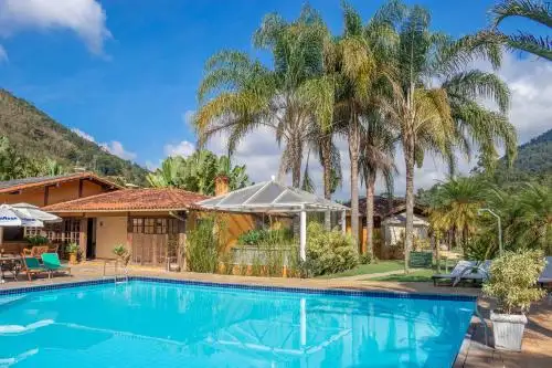 una casa con piscina y palmeras en Bomtempo Itaipava junto a Castelo Itaipava, en Itaipava
