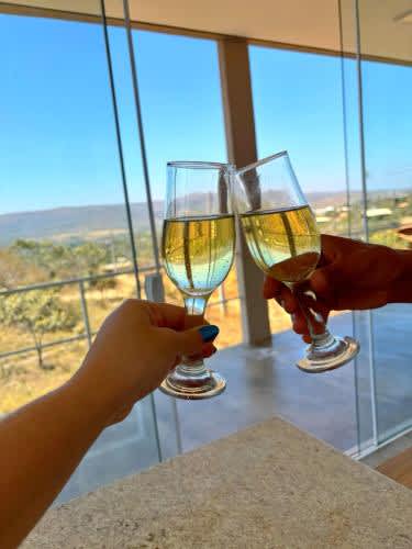 dos personas con copas de vino frente a una ventana en Villa Candombá, en Alto Paraíso de Goiás