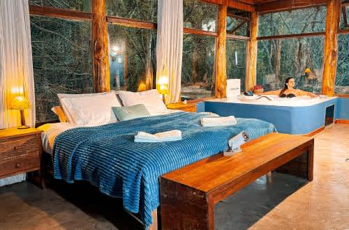 Un dormitorio con cama y bañera y una mujer en un baño en Alive Eco Hut Pousada, en Monte Verde