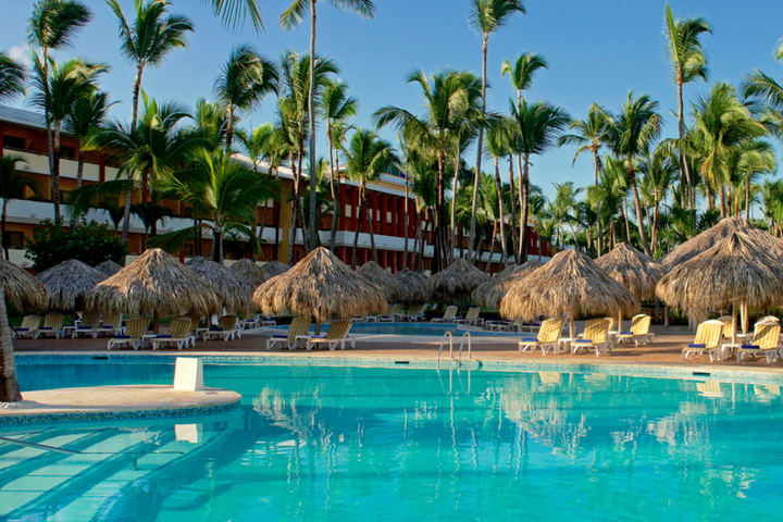 The pool area is equipped with sun loungers and palapas