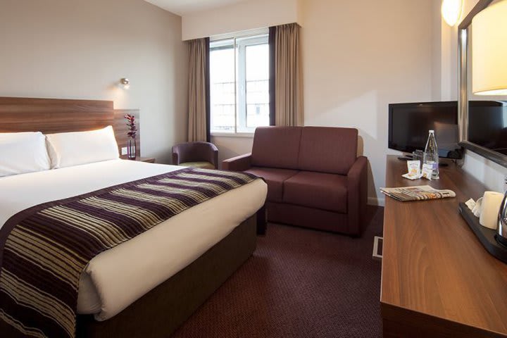 Habitación con mesa de trabajo y televisión de pantalla plana en el hotel Jurys Inn London Chelsea