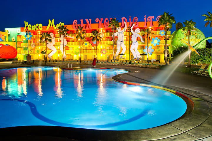 Vista nocturna de la piscina principal con una flor que lanza chorros de agua