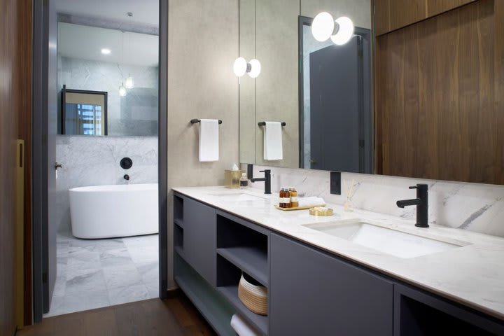 Baño con doble lavabo y bañera en una suite Luxe