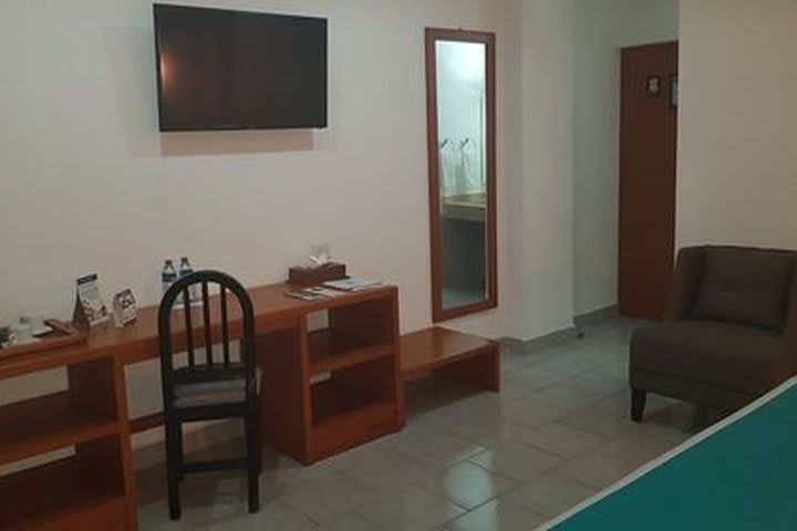 Vista a la habitación, cuenta con mesa de trabajo, televisión pantalla plana, cafetera y amenidades, armario y aire acondicionado